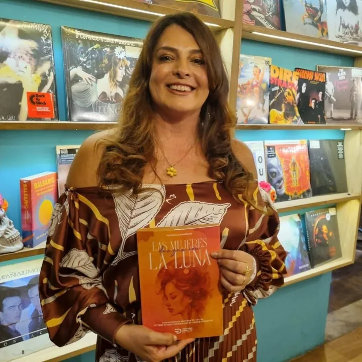 Patricia Casadiego sosteniendo su libro frente a una estantería de librería